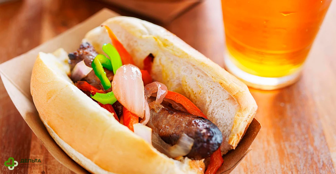 Стакан пива и хот-дог на столе